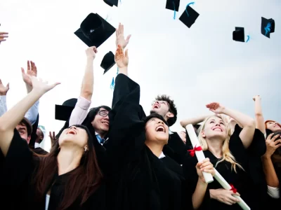 group-diverse-grads-throwing-caps-up-sky